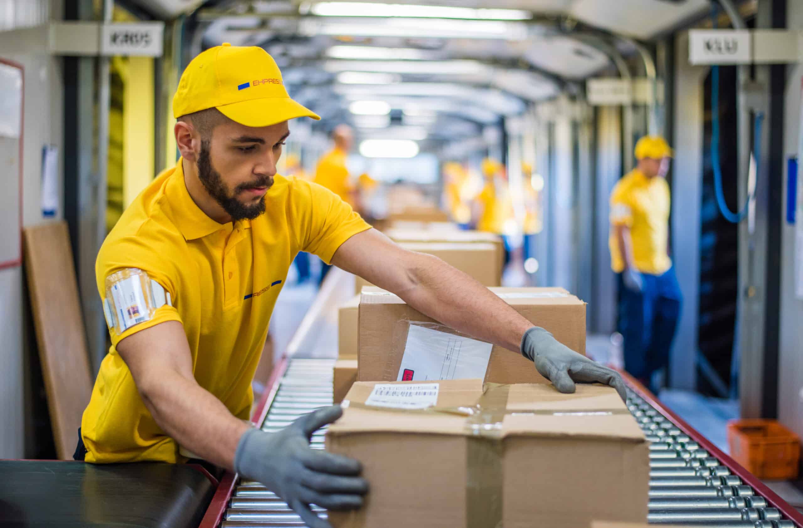 A package handler processes boxes on conveyor belt in distribution warehouse.